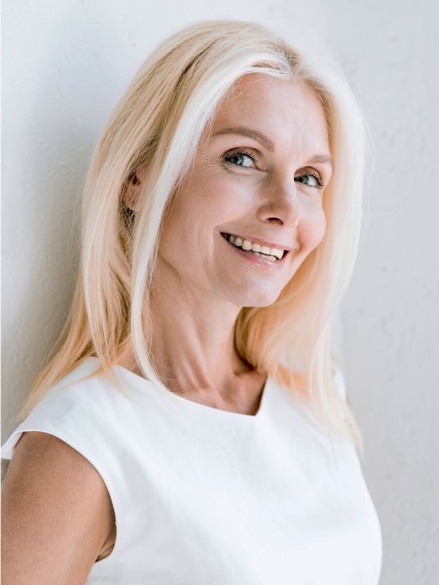 Smiling woman with long blonde hair and white top.