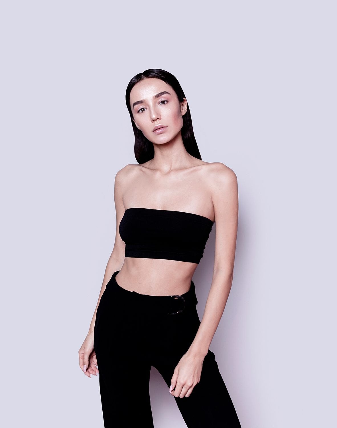 Model in black outfit against plain background.