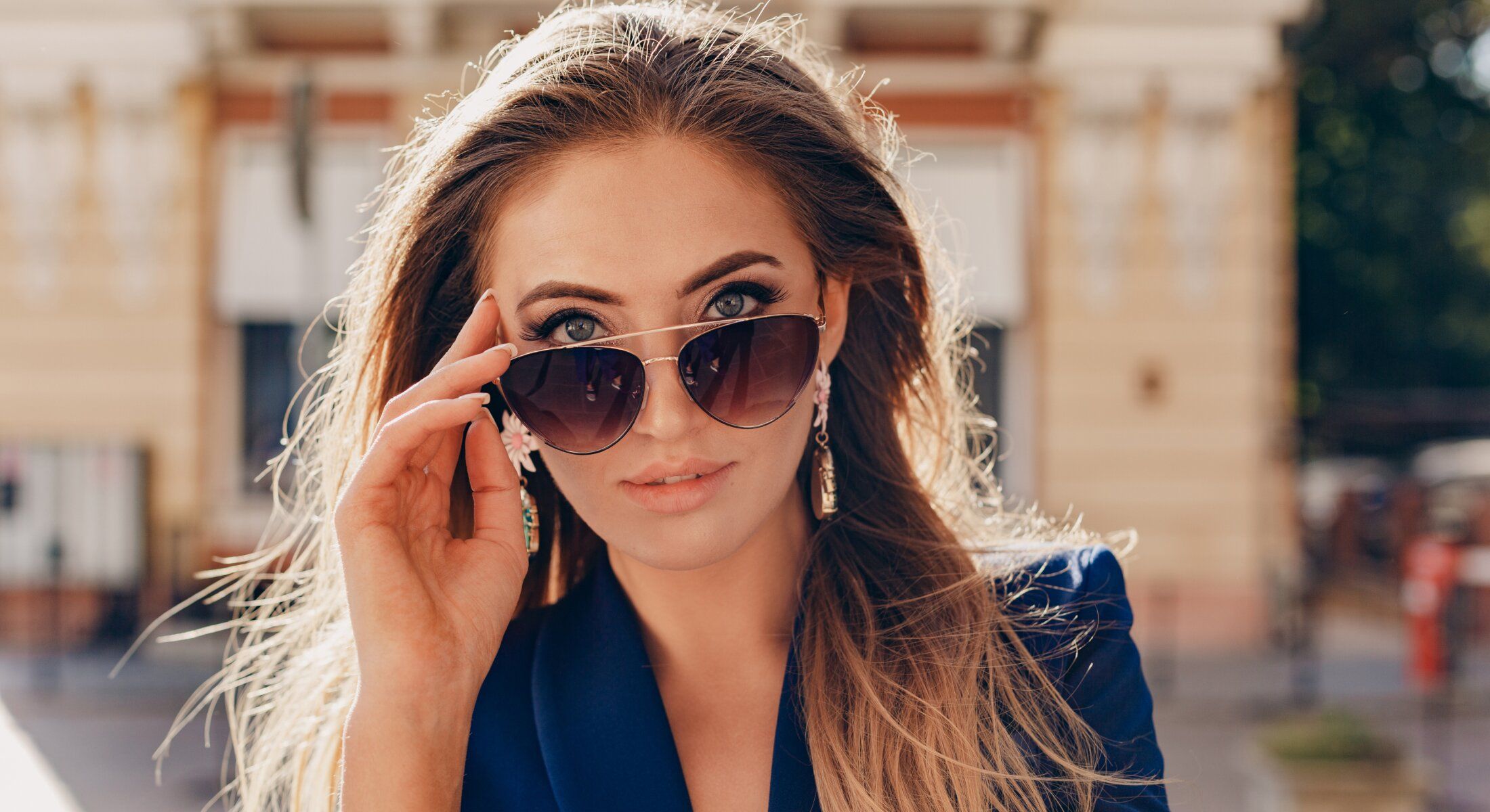 Woman with sunglasses and stylish earrings outdoors.